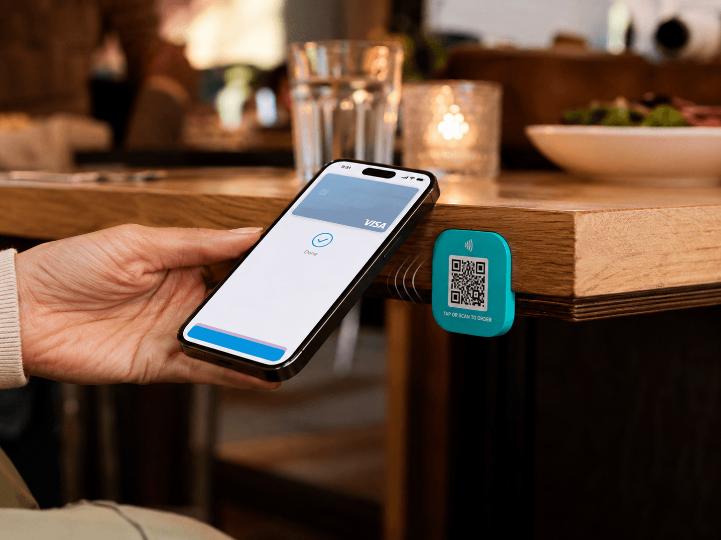 Person tapping phone to a Tapora NFC badge on a restaurant table to pull up the menu